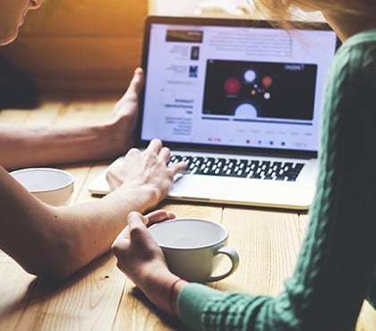 two people looking at article about it company on laptop