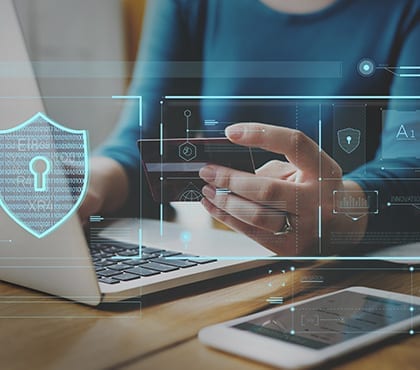 woman holding a credit card by her laptop with ransomware protection software installed