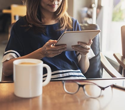 woman in cafe looking for an it consultant on her tablet